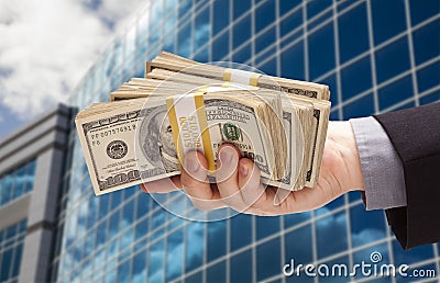 Male Hand Holding Stack of Cash with Corporate Building