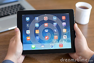 Male hands holding iPad with social media app on the screen in t