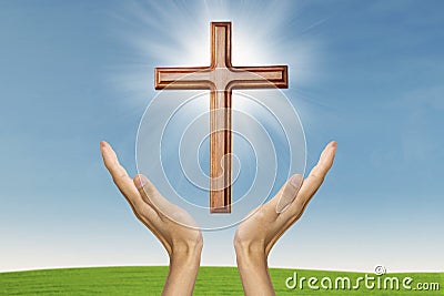 Male hands praying with a wooden cross