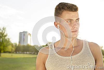 Male jogger looking away while listening music in park