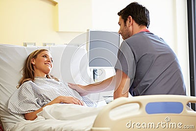 Male Nurse Talking With Female Patient In Hospital Room