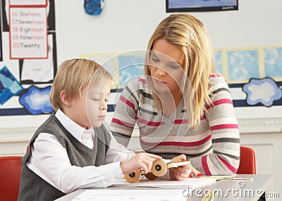Male Primary School Pupil And Teacher Working
