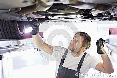 Male repair worker examining car in workshop
