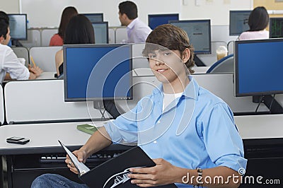 Male Student With Book In Computer Lab