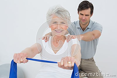 Male therapist assisting senior woman with exercises