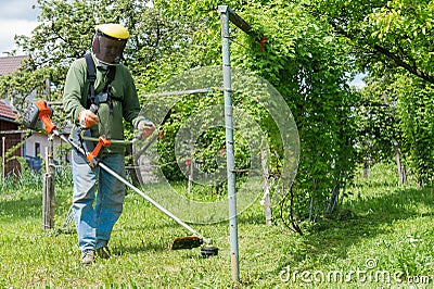 Male worker with power tool string lawn trimmer mo