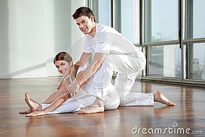 Male Yoga Instructor Assisting Woman