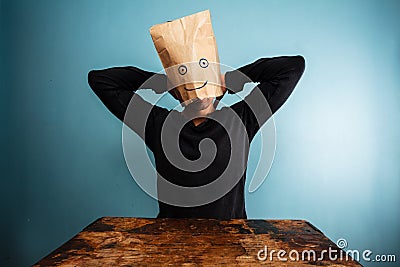 Man with bag over head relaxing at desk