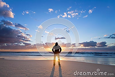 Man on the beach in front of rising sun