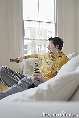 Man With Beer Bottle Watching TV On Sofa