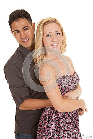 Man behind woman arms around her both smile looking