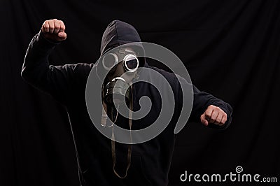 Man in black clothes wearing a classic gas mask over a dark back