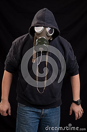 Man in black clothes wearing a classic gas mask over a dark back