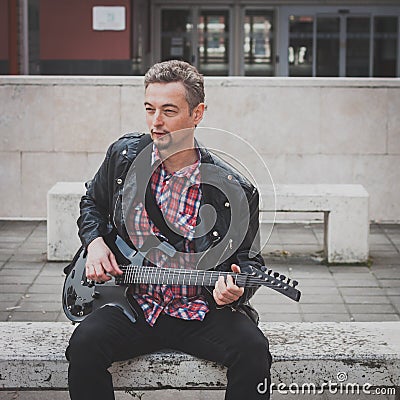 Man in black leather jacket playing electric guitar