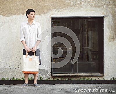 Man with canvas bag on grunge concrete wall