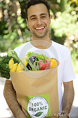 Man carrying recycle paper bag full of organic vegetable and fruits.