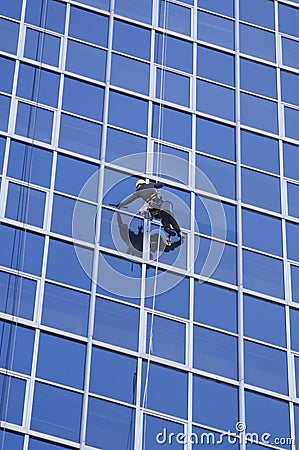 Man cleaning windows of modern business building