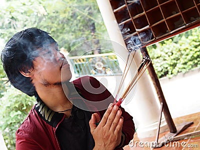 Man close his eyes and pray for buddha with joss stick