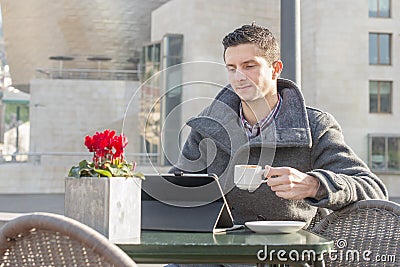 Man with coffee cup laptop computer in the terrace restaurant.