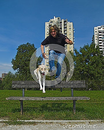 Man And Dog Jumping Over The Bench