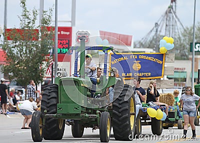 Man or farmer driving a large tractor in a parade in small town America