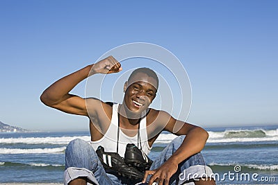 Man With Football Boots Around Neck Cheering On Beach