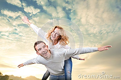 Man giving piggyback ride to girlfriend under the sky