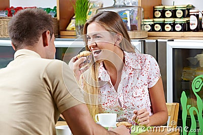 Man giving woman bite of muffin