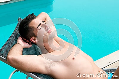 Man having a sun bath near a swimming pool