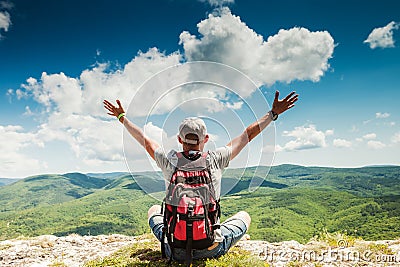 Man hiker greeting rich nature on the top of mountain