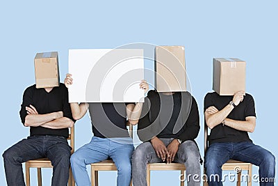 Man holding blank cardboard with male friends faces covered with boxes over blue background
