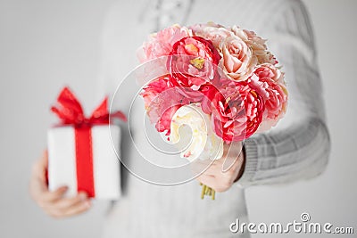 Man holding bouquet of flowers and gift box