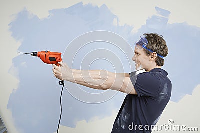 Man Holding Drill As Gun Against Wall