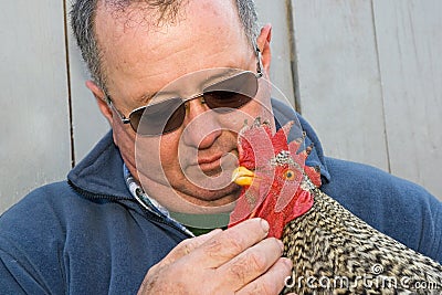 Man holding a rooster in his arms