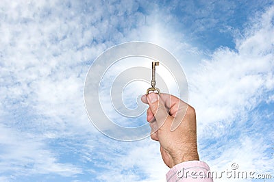 Man holding up key against bright sky