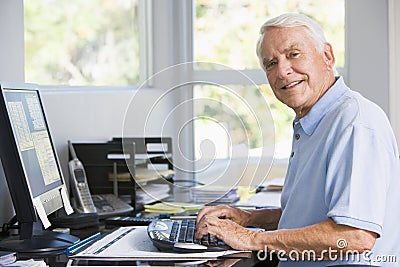 Man in home office using computer smiling