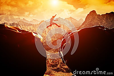 Man jumping over precipice between two mountains