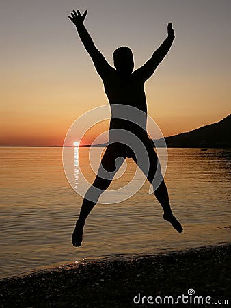 Man jumps in sunset at sea