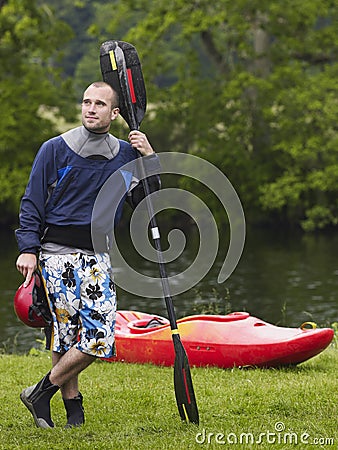Man With Kayak Paddle Standing On Grass