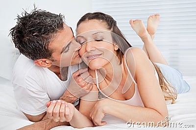 Man kissing woman in bed