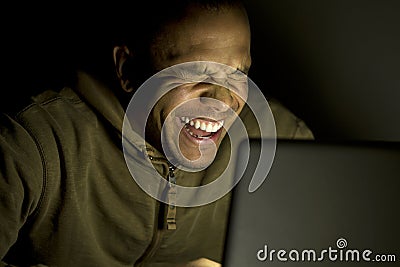 Man laughing at his laptop at night