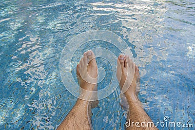 Man legs at blue water of swimming pool