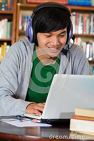 Man in library with laptop and headphones