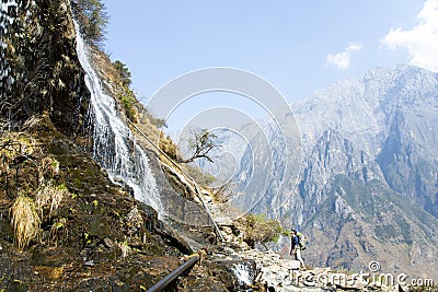 Man Looking Up at Mountainside Waterfall