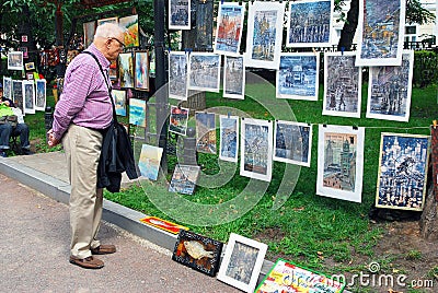 A man looks at paintings shown on Gogol boulevard.