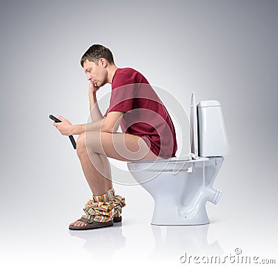 Man with mobile phone sitting on the toilet
