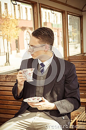Man with mustache and glasses on train wooden wagon drinking cof