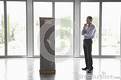 Man Observing Package In Empty Office