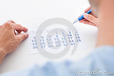 Man with pen looking at calendar