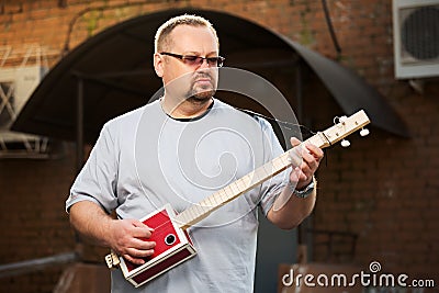 Royalty Free Stock Images: Man playing cigar box guitar